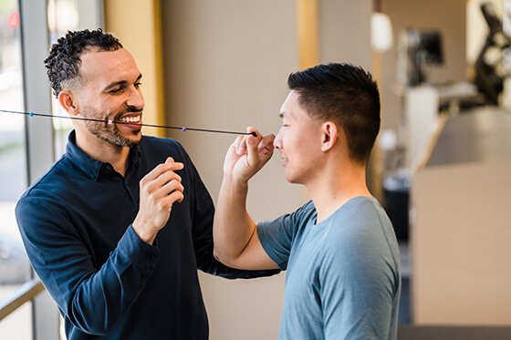 A male physical therapist working with a male patient on eye exercises. 