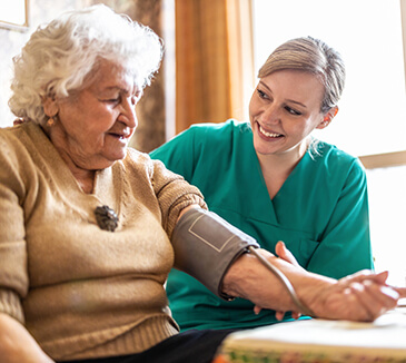 Therapist taking blood pressure of patient in their home
